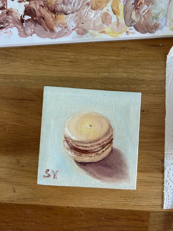 Honey macaron oil painting on the studio worktable, with a paint palette